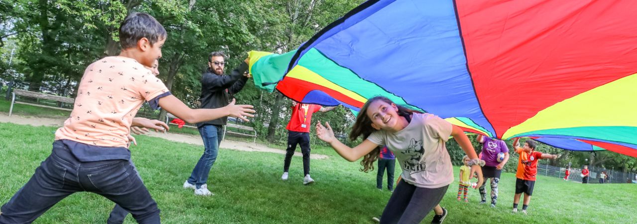 Kinder spielen im Park mit einem Flattertuch