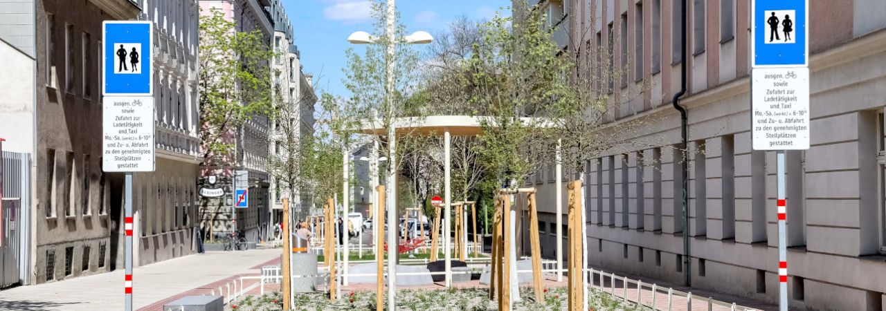 Ansicht eines Straßenzugs im Supergrätzl mit neu gepflanzten Bäumen und entsiegelten Flächen.