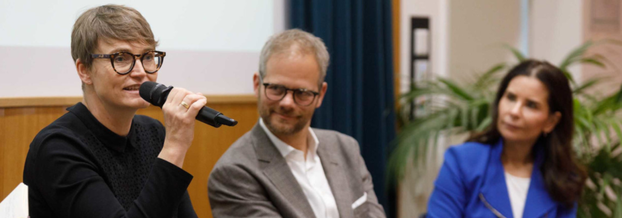 Eva Czernohorszky spricht bei einer Konferenz, daneben Klemens Himpele und Sonja Kato