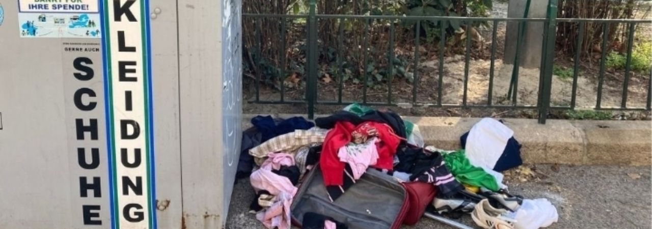 Разпръснати дрехи около контейнер за отпадъци